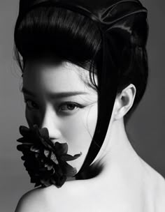 a woman with a flower in her hair is posing for a black and white photo