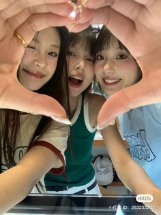 two girls are making heart shapes with their hands