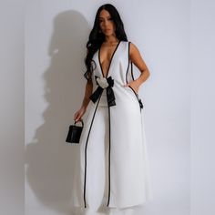 White Sleeveless Long Top With Sleek Black Trim And A Chic Black And White Floral Accent At The Waist. The Long Top Drapes Beautifully And Enhances Your Figure With Its Flattering Silhouette. The Contrasting Black Trim Adds A Touch Of Refinement, While The Floral Accent Infuses The Outfit With A Vibrant Pop Of Color And Charm. Black And White Jumpsuit Outfit, Polyester Pants, Gilet Long, Long Vests, Tank Top Dress, Bow Detail Dress, White Pants, Black Trim, Sleeveless Tank