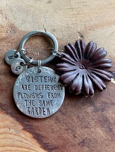 there is a keychain that says sisters are different flowers from the same garden