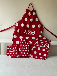 a red apron with white polka dots and symbols on it, sitting on a table