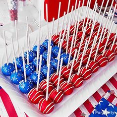 a tray filled with red, white and blue cake pops on top of a table