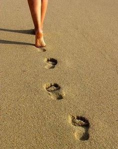 a woman walking down the beach with her feet in the sand and a quote written on it