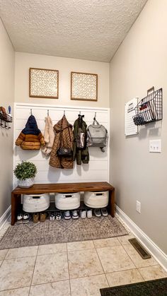 a coat rack filled with coats and shoes next to a tiled floor in a home