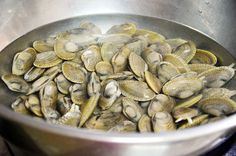 clams are being cooked in a large metal bowl