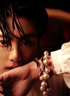 a woman wearing a bracelet with pearls on it's wrist and looking at the camera