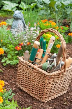 a basket filled with gardening tools sitting in the middle of a garden surrounded by flowers