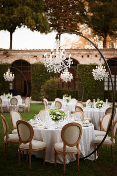 an outdoor dining table with chandelier hanging from it's centerpieces