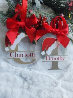 two personalized christmas ornaments with red bows