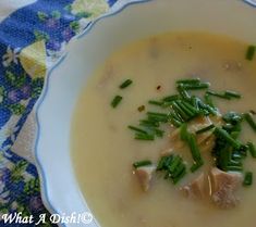 a white bowl filled with soup and green onions on top of a blue table cloth