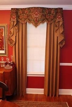 a living room with red walls and wooden flooring, curtains on either side of the window