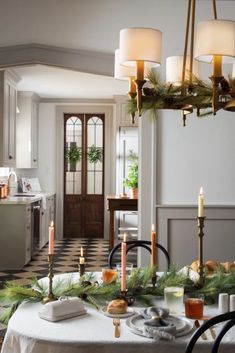 a dining room table is decorated with candles and greenery for the holiday tablescape