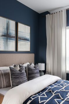 a bedroom with blue walls and white bedding, two framed pictures on the wall