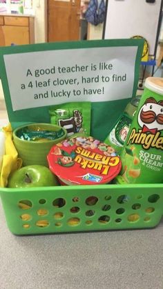 a green plastic basket filled with lots of food and candy next to a sign that says, a good teacher is like a 4 leaf clover, hard to find and lucky to have