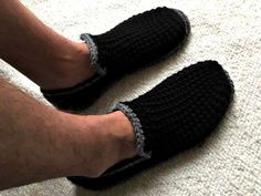 a man wearing black slippers on top of a white carpeted floor with his feet in the air