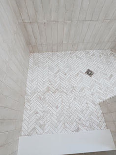 a white tiled shower stall with a black and white tile design on the wall next to it