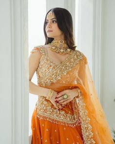 a woman in an orange lehenga and gold jewelry