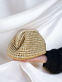 a woman's hand is holding a gold purse