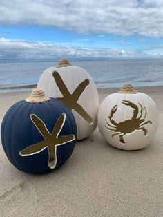 three painted pumpkins sitting on top of a sandy beach