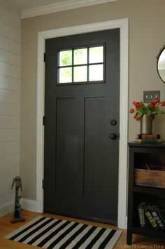 a black front door with a white and black striped rug on the floor next to it