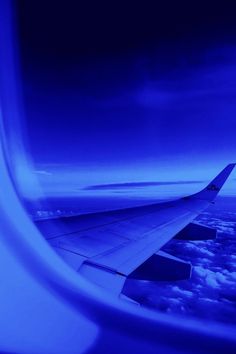 the wing of an airplane as seen from above in the sky with clouds and blue hues