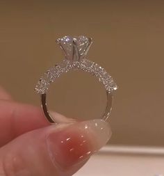 a person holding a diamond ring in their hand