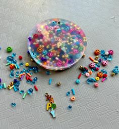 there are lots of colorful beads and buttons on the floor next to a button case