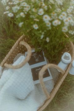 a basket filled with white towels sitting next to a flower pot on top of a grass covered field