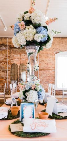 a tall vase filled with white and blue flowers on top of a table covered in cards