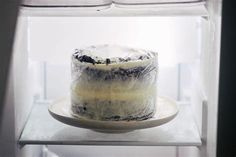 a cake sitting on top of a white plate in a glass case next to a window