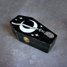 an open black box with white designs on the lid and a crescent in the middle