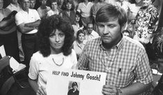 a man and woman holding a sign in front of a crowd