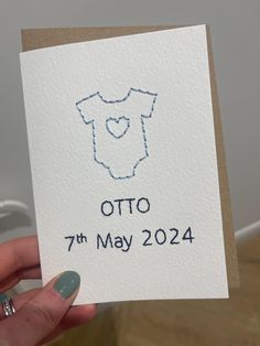 a hand holding up a card with the name otto on it in blue ink