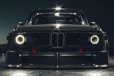 the front end of a black car with headlights on