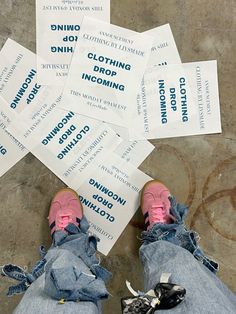 someone's feet with pink shoes and blue jeans are surrounded by coupons on the floor