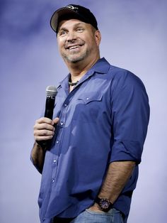 a man holding a microphone in his right hand and wearing a baseball cap on top of his head