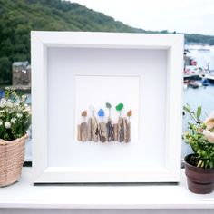 three small wooden sticks are arranged in front of a white frame with flowers on it