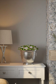 a flower pot sitting on top of a white table next to a lamp and chair