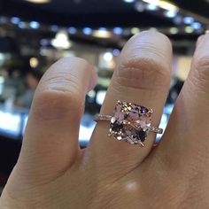 a person's hand holding an engagement ring with two stone stones on the band