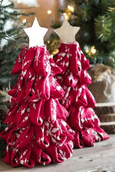 two red christmas trees sitting on top of a wooden table next to a tree with white stars