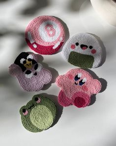 four crocheted animal coasters sitting on top of a white cloth covered table