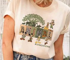 a woman wearing a t - shirt that says kingdom with cartoon characters on the front