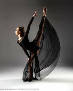 a woman in black is dancing with her arms spread out to the side and hands behind her head