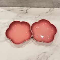 two pink dishes sitting on top of a marble counter