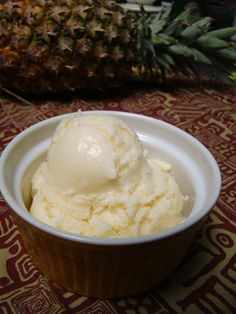 a bowl filled with ice cream next to a pineapple