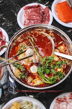 several plates of food on a table with utensils in them and meats