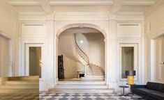 a room with a checkered floor and white walls has a spiral staircase in the center