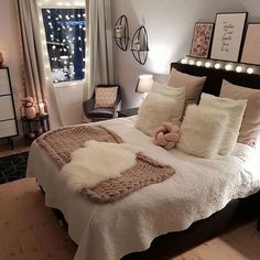 a bedroom with white bedding and lights on the window sill, wooden flooring