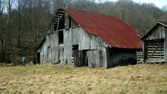 an old barn with a red roof in the woods