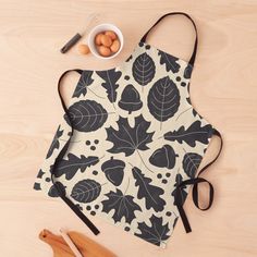 an apron with leaves and acorns on it next to wooden utensils